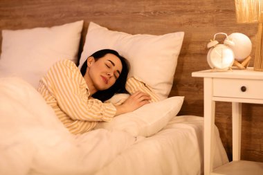 Geceleri yatakta uyuyan güzel bir genç kadın.