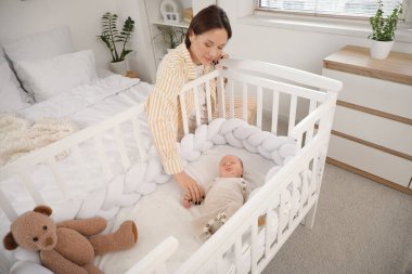 Mutlu anne ve onun tatlı bebeği evde beşiğinde uyuyorlar.