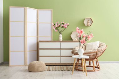 Oturma odasının içinde vazolarda koltuk, tuvalet ve manolya çiçekleri var.