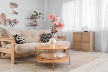 Masada vazo içinde kanepe, çekmece ve manolya çiçekleri olan oturma odasının içinde.