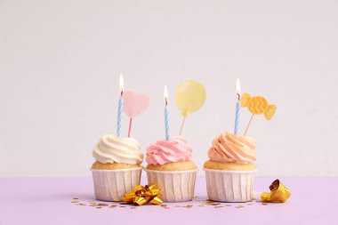 Tatlı doğumgünü kekleri yanan mumlar ve renkli arka planda parti düdüğü.