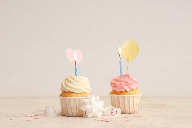 Beyaz arka planda yanan mumları ve konfetisi olan tatlı doğum günü kekleri.