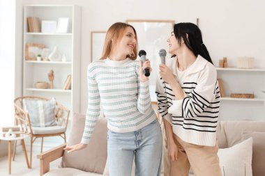 Evde mikrofonlu güzel genç kadınlar karaoke yapıyor.