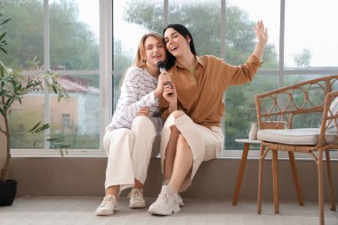 Evde mikrofonlu güzel genç kadınlar karaoke yapıyor.