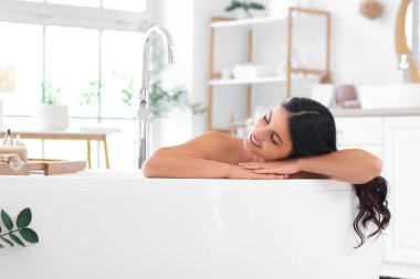 Güzel, genç ve mutlu bir kadın evde küvette dinleniyor.