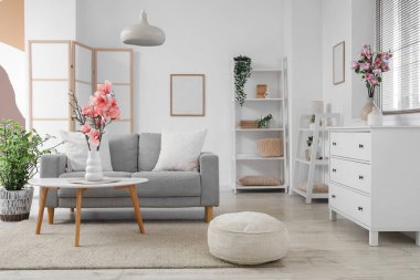 Oturma odasının içinde manolya çiçekleri olan kanepe ve kahve masası.