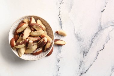 Beyaz arka planda lezzetli Brezilya fındıkları olan kase