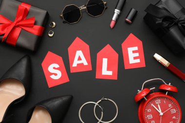 Satış sözcüğü, şık kadın aksesuarları, kozmetik ürünleri ve koyu arkaplanda hediyeler içeren kompozisyon