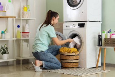 Sepetli genç bir kadın odada çamaşır yıkıyor.