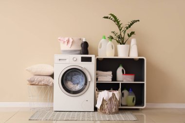 Çamaşır makinesi, raf ünitesi ve deterjanı olan bir çamaşırhane.