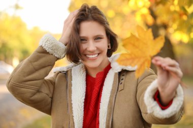 Sonbahar parkında yaprakları dökülen genç ve güzel bir kadın.