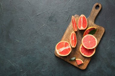 Tahta tahta tahta, kesilmiş greyfurtlar ve koyu arkaplanda yapraklar.