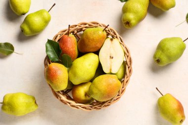 Beyaz arka planda tatlı olgun armutlarla dolu bir hasır kase.