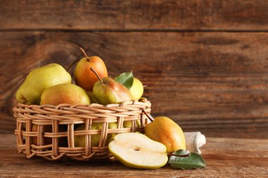 Ahşap zemin üzerinde tatlı olgun armutlar olan hasır kase.