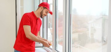 Erkek işçi dairedeki pencereyi tamir ediyor.