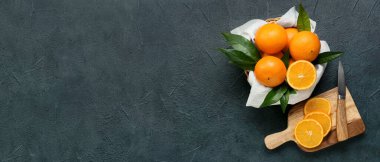 Bir sepet taze, sulu portakal, kesme tahtası ve bıçak koyu arkaplanda metin için yer, üst görünüm