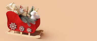 Noel süslemeleri ile dekoratif kızak ve bej arkaplan üzerinde hediyeler metin için alan