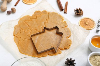 Hafif arka planda lezzetli Noel kurabiyeleri hazırlamak için hamur, kesme makinesi ve baharatlar.