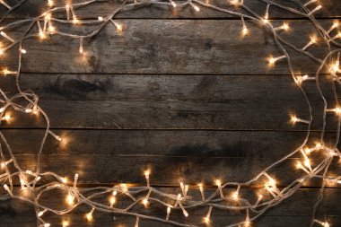 Koyu ahşap arka planda parlayan Noel ışıklarından yapılmış çerçeve