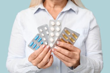 Mavi arka planda hapları olan güzel olgun bir kadın.