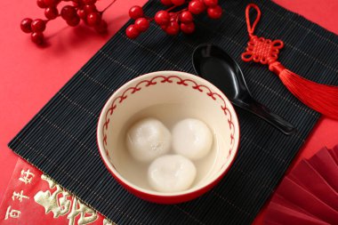 Kırmızı arka planda bir kase Tangyuan ve Çin dekoru. Dongzhi Festivali