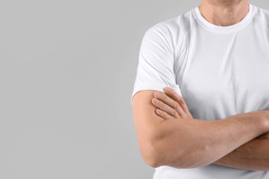 Gri arka planda çapraz kollu, orta yaşlı sporcu, yakın plan.