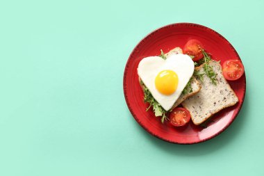 Turkuaz arka planda lezzetli yumurta, tost, domates ve roka tabağı.