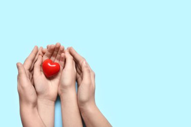 Mavi arka planda kırmızı kalp tutan kadın ve çocuğun elleri