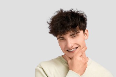 Hafif arka planda diş telleri olan gülümseyen genç adam.