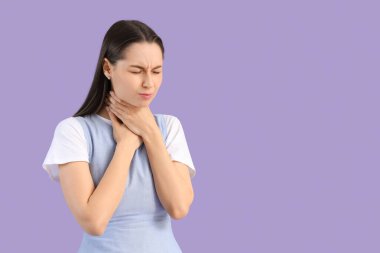 Leylak arka planında boğaz ağrısı çeken genç bir kadın.