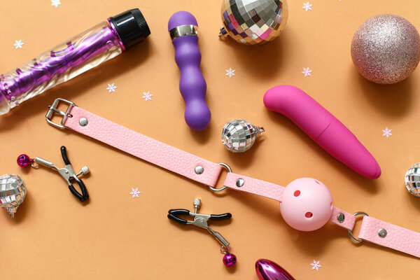 Различные секс-игрушки и рождественский декор на оранжевом фоне