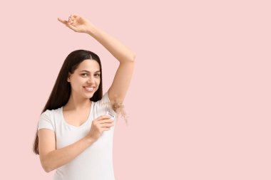 Güzel, genç ve mutlu bir kadın, kuru sazlıklar ve pembe arka planda modern bir epilatorle. Yasaklama kavramı