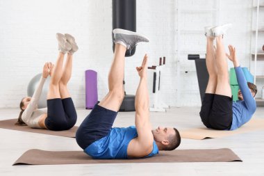 Sporty young people training with coach on mats in gym