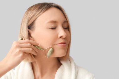 Gri arka planda masaj tekerleği olan kadın.