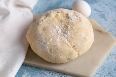 Mavi zemin üzerinde taze hamur ve yumurta olan tahta.