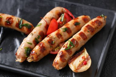 Lezzetli ızgara sosis, soğan ve domatesli siyah arka plan.