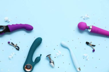 Meme ucu kıskaçlı farklı vibratörler ve mavi arka planda anal tıkaçlar.