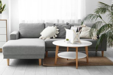 Gri kanepeli, yumuşak yastıklı ve kahve masalı şık bir oturma odası.