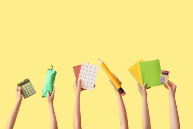 Okul malzemeleri ve sarı arka planda kalem kutusu olan kadın eller.