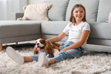 Kral Charles 'ın köpeğiyle birlikte oturma odasında halının üzerinde oturan tatlı küçük kız.