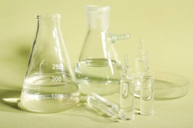 Yeşil arka planda laboratuvar camları olan tıbbi ampuler.