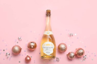Bir şişe şampanya ve pembe arka planda konfeti.
