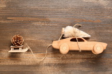 Oyuncak araba ve küçük Noel ağacıyla kızak ve tahta arka planda çam kozalağı
