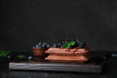 Taze böğürtlen, yabanmersini ve siyah arkaplanda nane şekerli Belçika waffle 'ı.