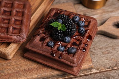 Tahta arka planda taze böğürtlen ve yabanmersinli Belçika waffle 'ı.