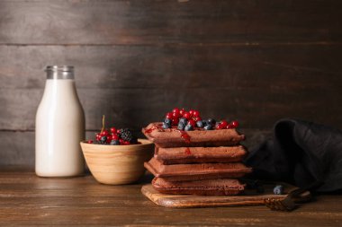 Taze yaban mersinli Belçika waffle 'ı, kırmızı frenk üzümü ve tahta arka planda bir şişe süt.