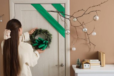 Koridordaki kapıya güzel bir Noel çelengi asan kadın