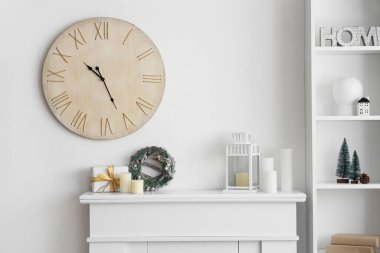 Noel dekorlu şömine, duvardaki saat ve oturma odasının içindeki raf ünitesi.