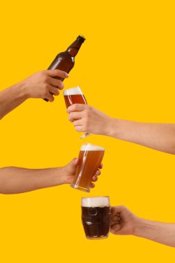 Sarı arka planda soğuk bira bardakları olan erkek elleri. Ekim Festivali Kutlaması