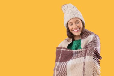 Sarı arka planda ekose şapkalı genç bir kadın.